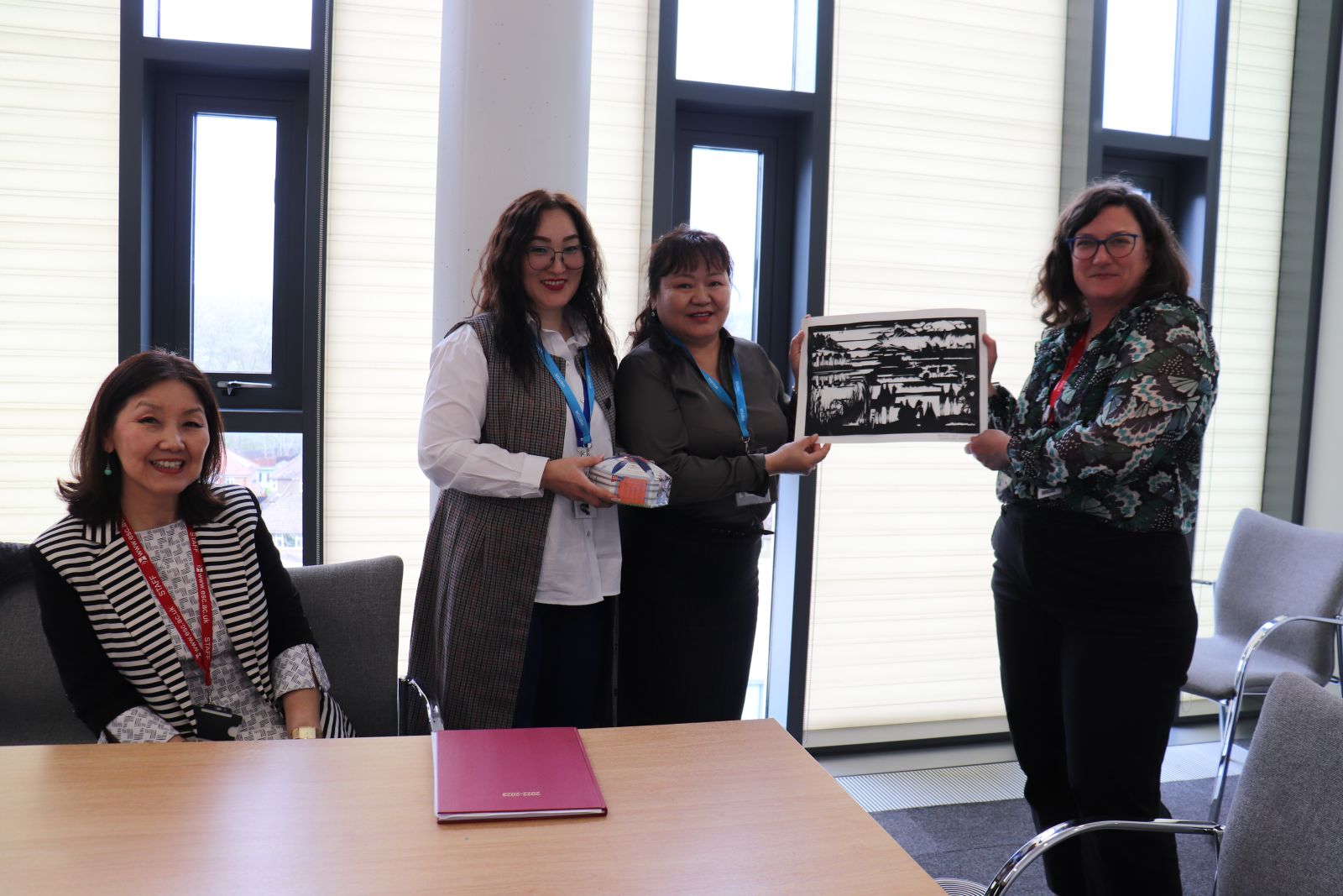 Meg Conacher and Rebecca Taylor being presented with a painting from two Mongolian visitors