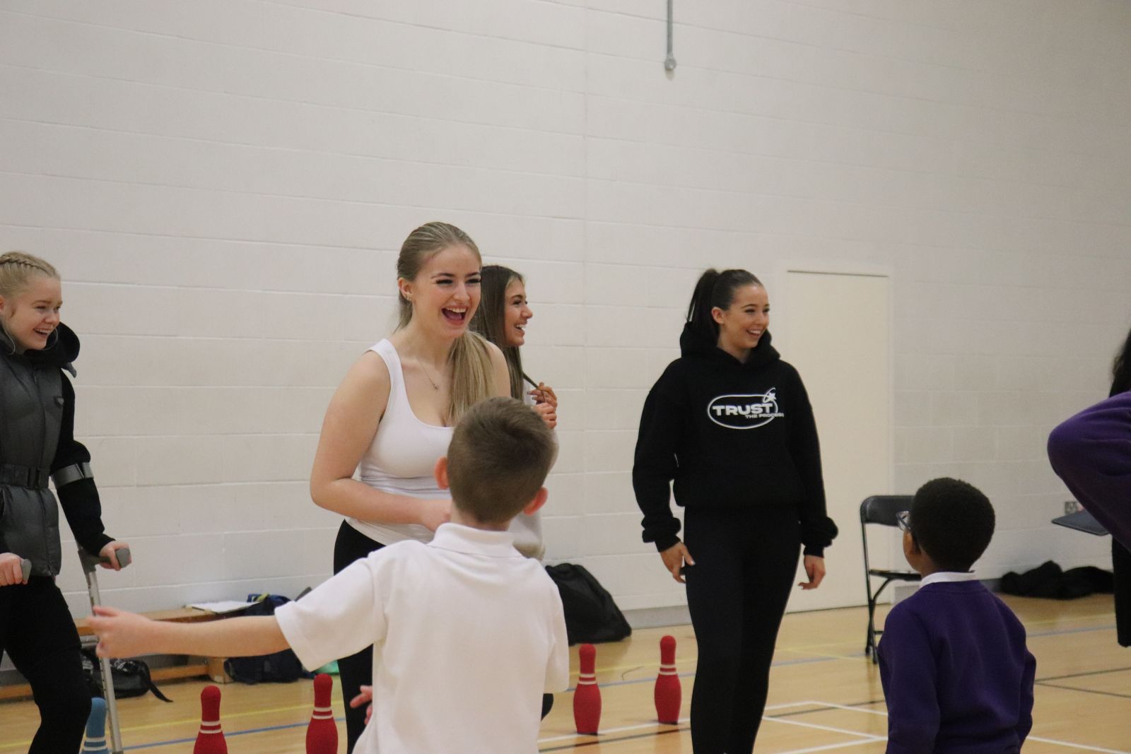 Students laughing and smiling with children whilst coaching
